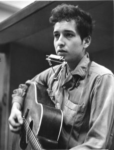 NOVEMBER 1961:  Bob Dylan recording his first album, "Bob Dylan", in front of a microphone with an acoustic Gibson guitar and a harmonica during one of the John Hammond recording sessions in November 1961 at Columbia Studio in New York City, New York. (Photo by Michael Ochs Archives/Getty Images)